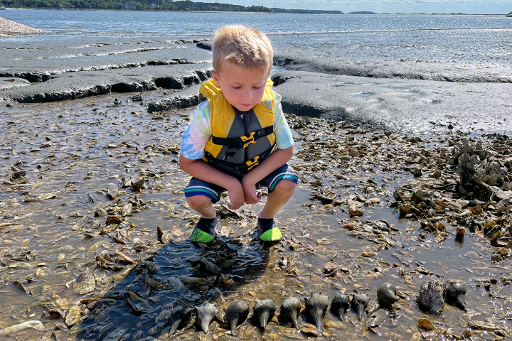 a little boy standing next to a body of water