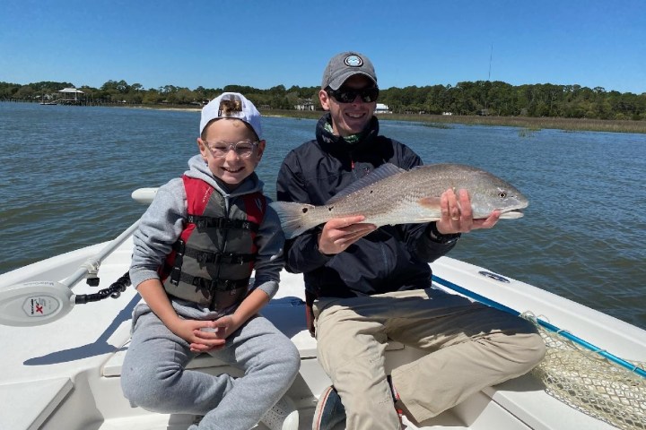 a person holding a fish on a boat in a body of water